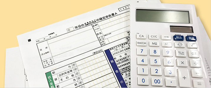 確定申告書の上に計算機が置かれたイメージ画像